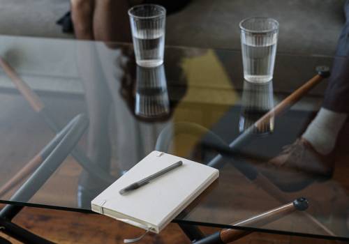 notebook and two glass cups on a glass table